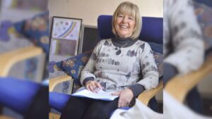 Smiling woman sitting, reading documents.